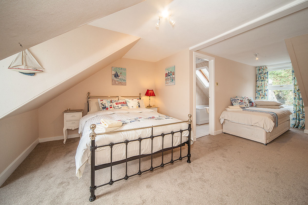 Double bed in large room with white walls and cream coloured carpet