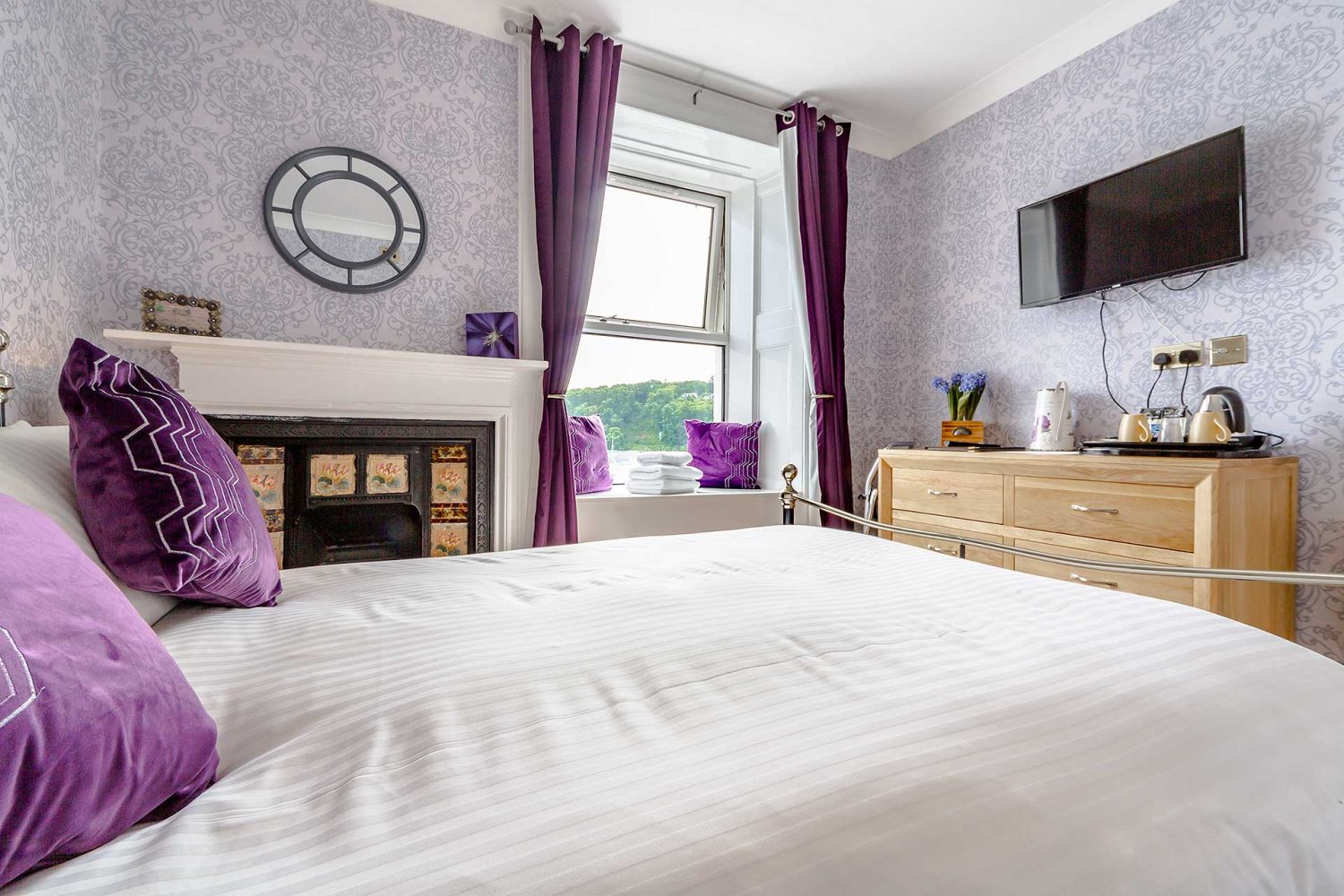 purple bedroom with double bed and window seat